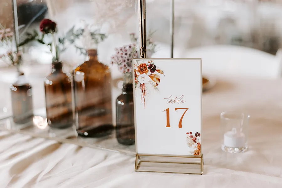 Boho table setting with amber bottles, dried florals, and a table number