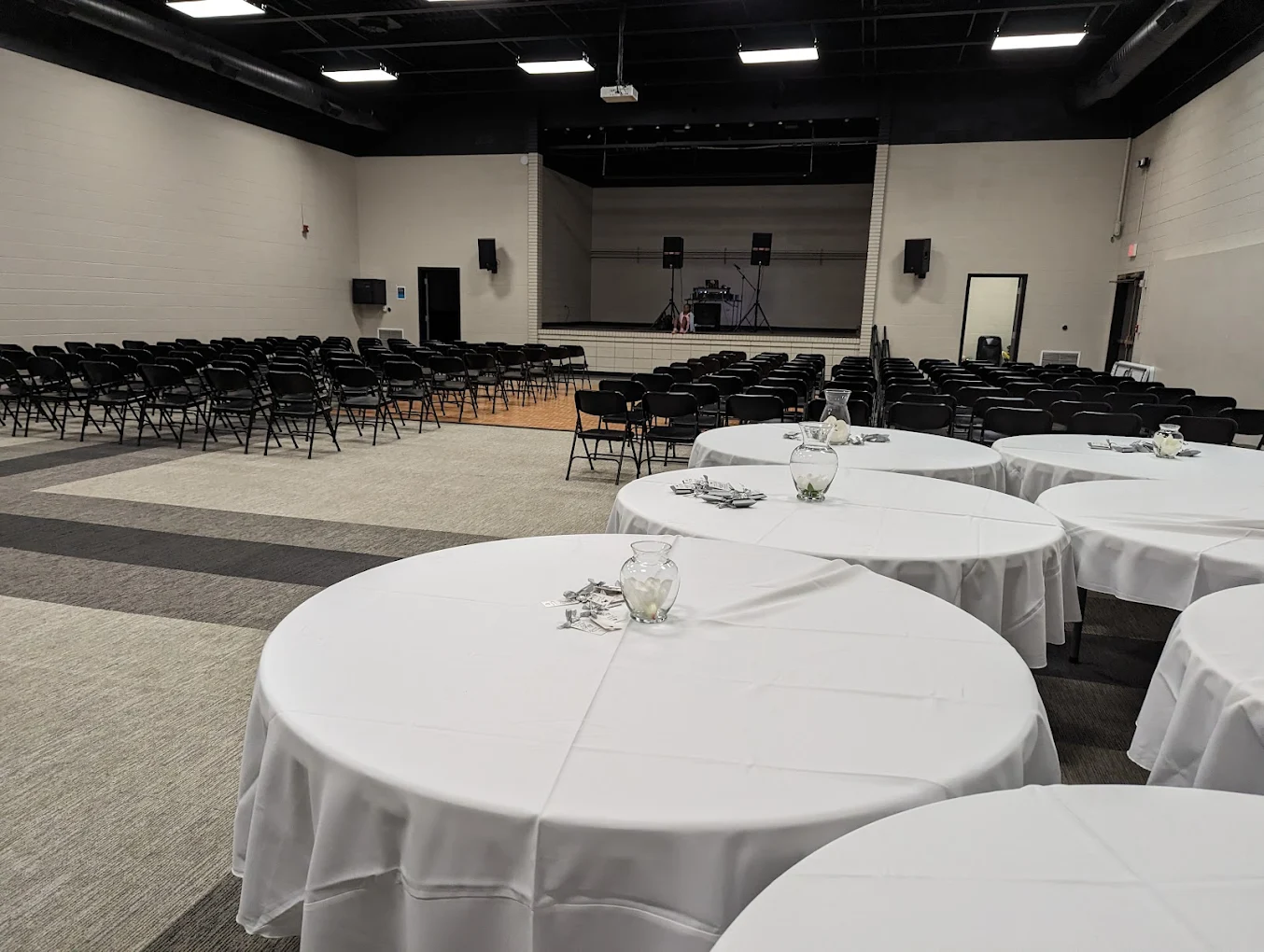 Round tables with white linens in the quiet hall at SandHills Event Center